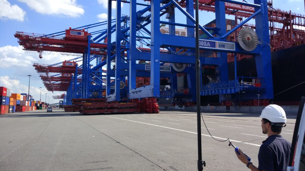 Ein Schiffsakustischer Ingenieur steht im Hamburger Containerhafen in der Nähe eines Containerschiffs. Er hält ein Messgerät in der Hand, um den vom Schiff erzeugten Lärm in der Umgebung zu messen. 