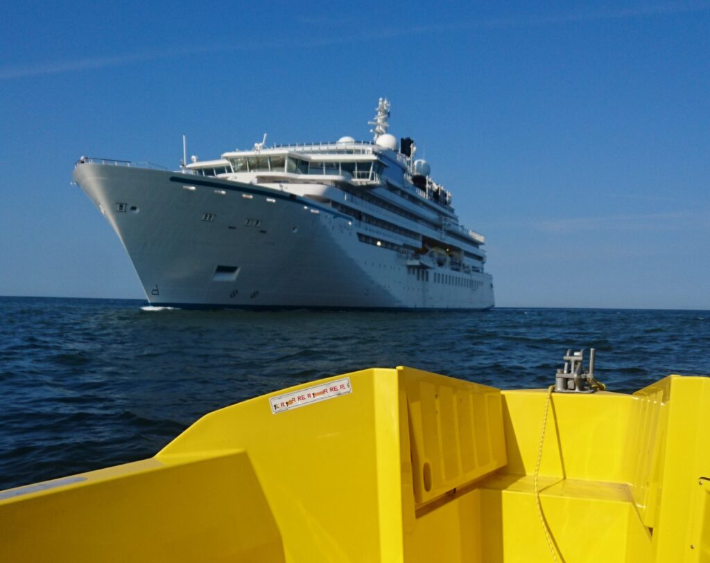 Ein Expeditionskreuzfahtschiff fährt an einer Unterwasserschallmessstelle vorbei. Abgestrahlter Unterwasserschall wird aufgezeichnet, um anschließend ausgewertet zu werden. 
